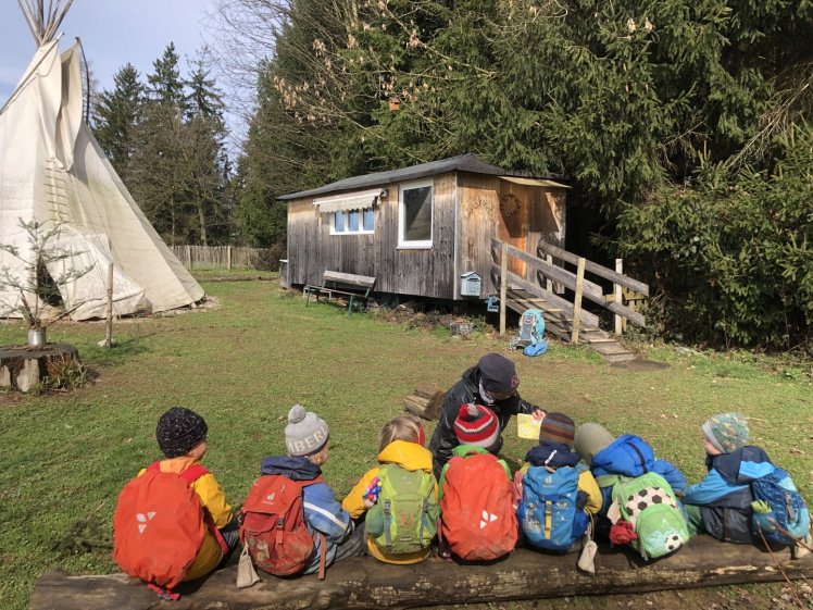 Eine Gruppe von Menschen, die vor einem Haus auf dem Boden sitzen